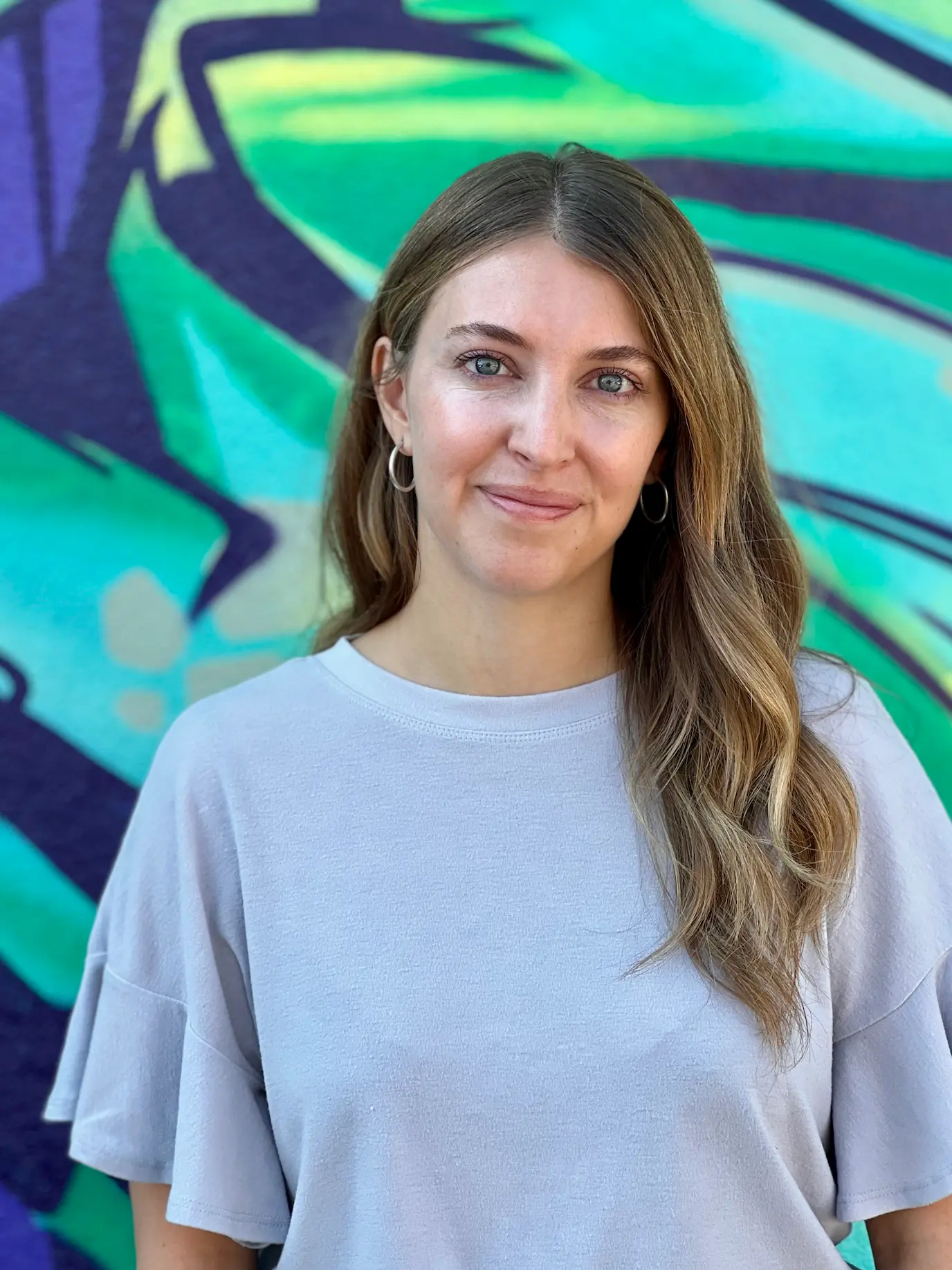 Tessa Malsam headshot standing outside in front of a colorful wall